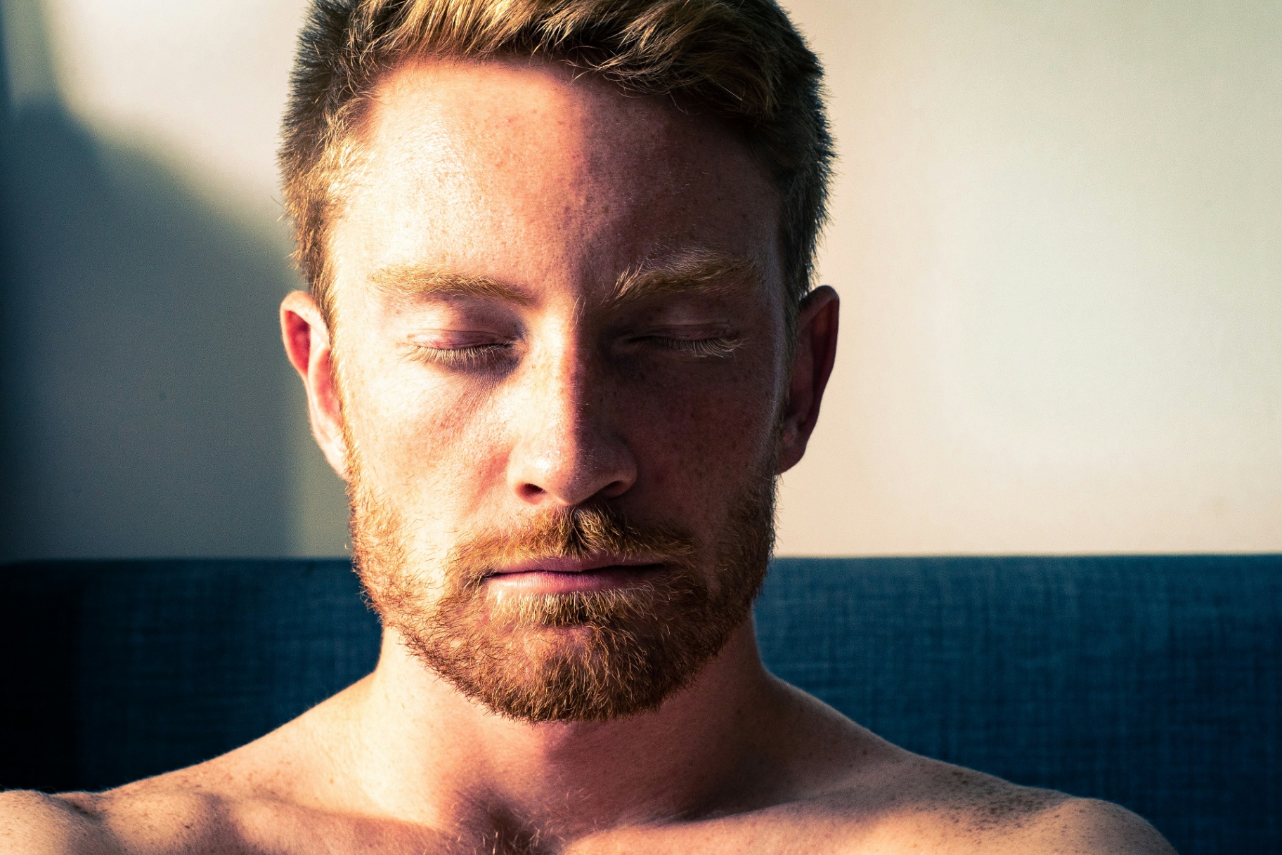 Close-up portrait of a man with eyes closed in warm light